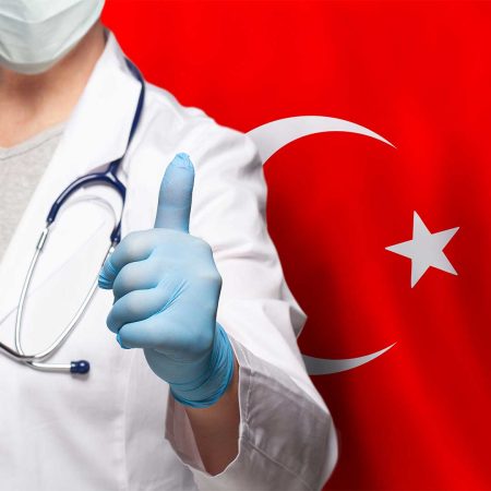 Doctor in medical attire giving thumbs up with Turkish flag in background, symbolizing trust and high-quality healthcare in Turkey